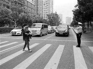 协警手持礼让牌站在斑马线前提醒来往车辆 记者 吴依滢 摄